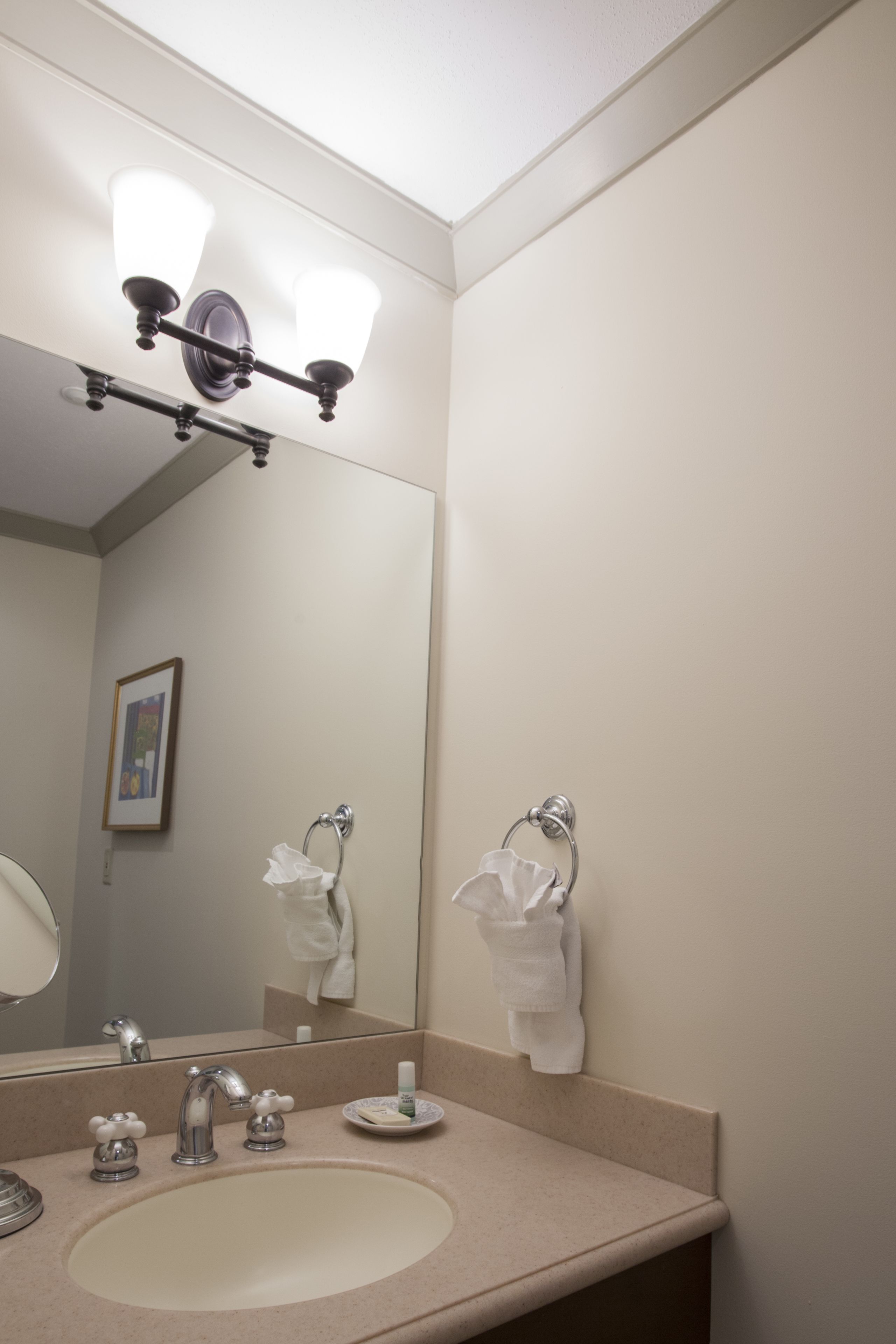 A bathroom with a sink, mirror, towel rack, and a light fixture above the mirror.
