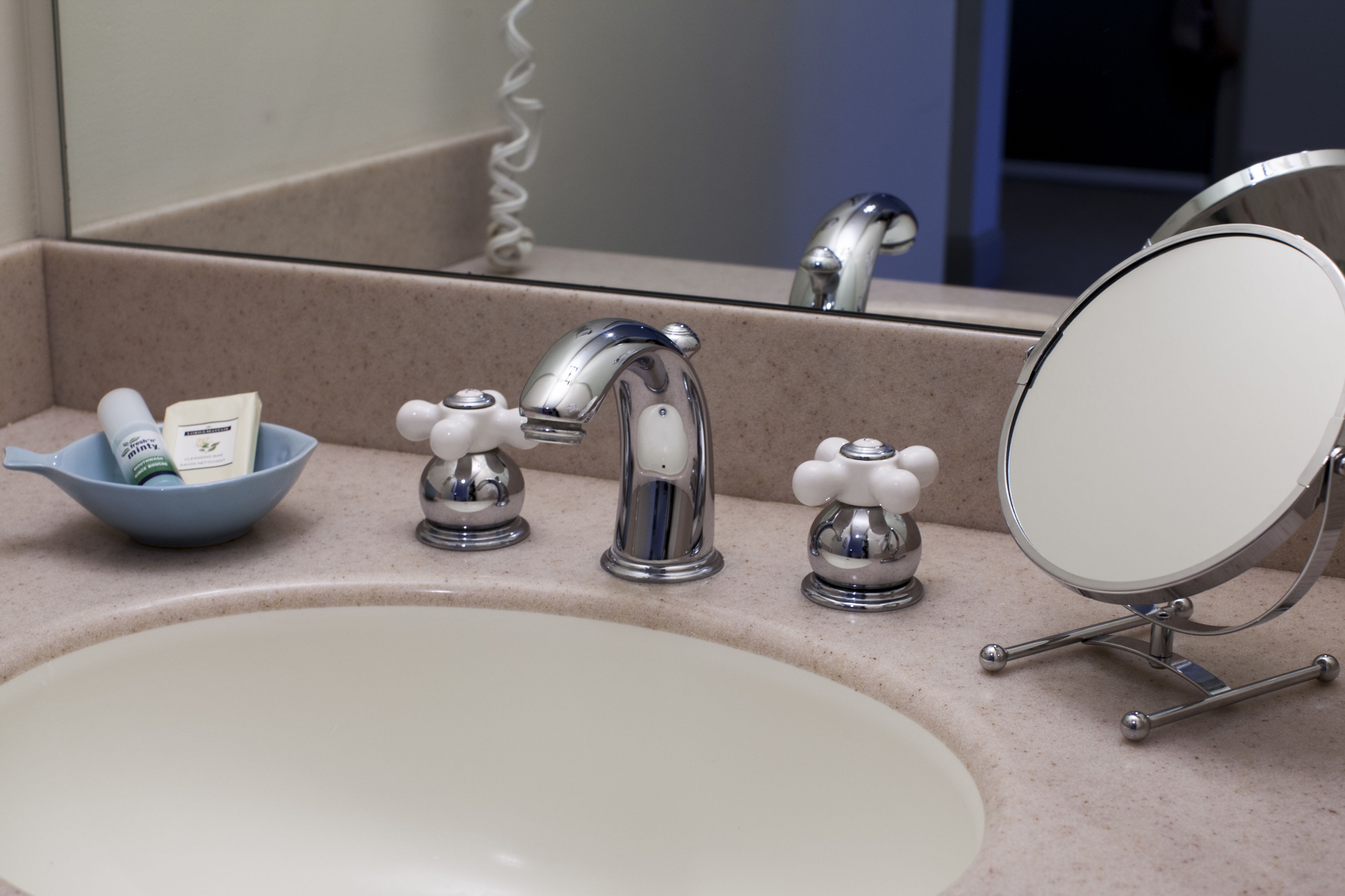 Un lavabo con espejo, un jabonera y un dispensador de jabón.