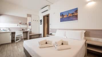 Een hotelkamer met een bed, een bureau, een stoel, een kledingkast en een wandairconditioner.