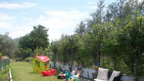 A backyard with a playhouse, a slide, and outdoor furniture. - Varelis (Rhodes)