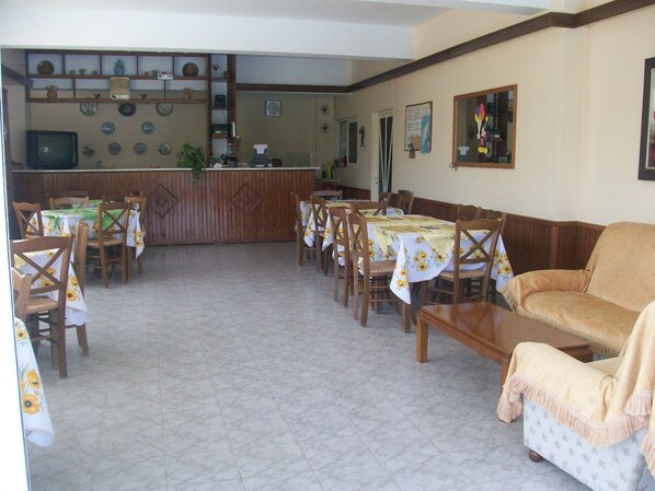 Un espace repas avec des tables et des chaises, un coin cuisine avec un comptoir et un canapé.