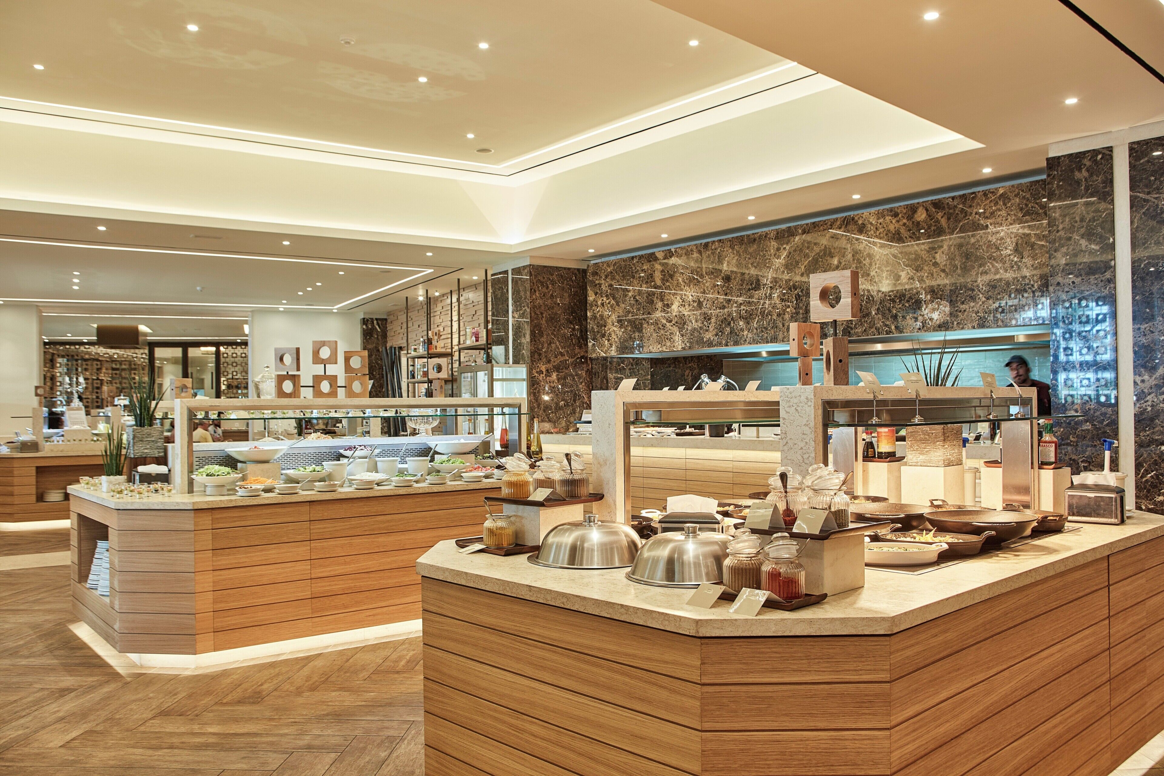 Un espace buffet agrémenté d’un mur en marbre, d’un comptoir en bois et de divers plats.