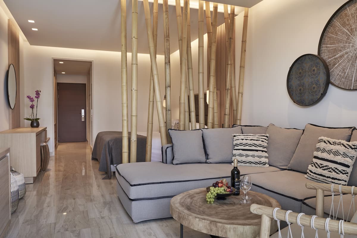 A modern living room with a sofa, a round wooden coffee table, and a decorative wall panel.