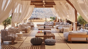 Un espace de détente extérieur aménagé avec des meubles en osier, une pergola en bois et une vue sur un paysage montagneux.