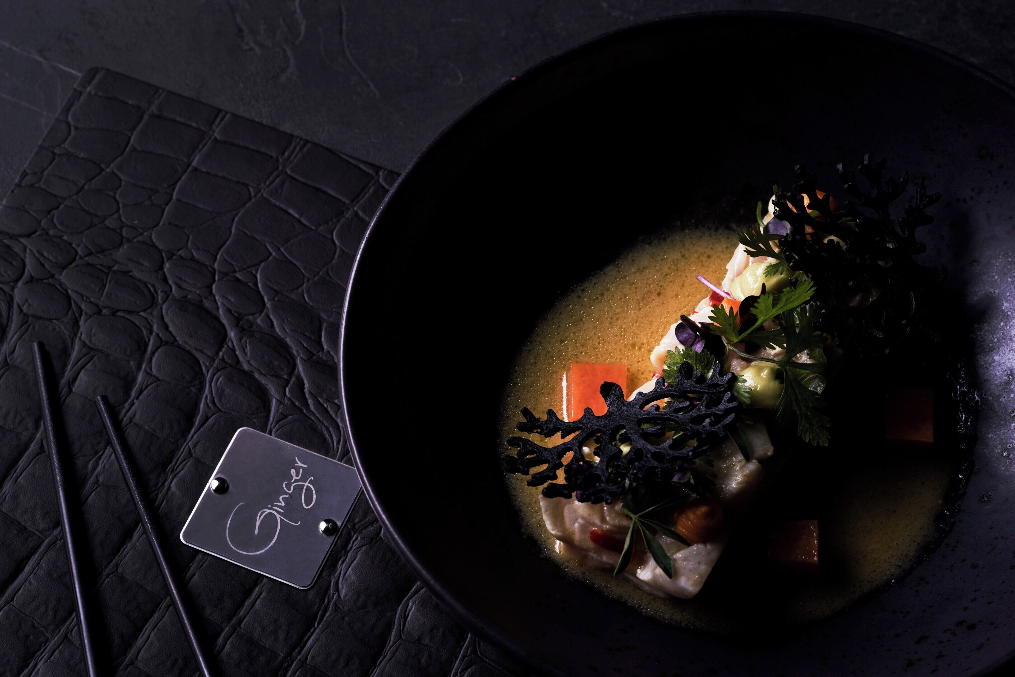 Une table sombre, à la surface texturée, avec des baguettes et une étiquette en métal.