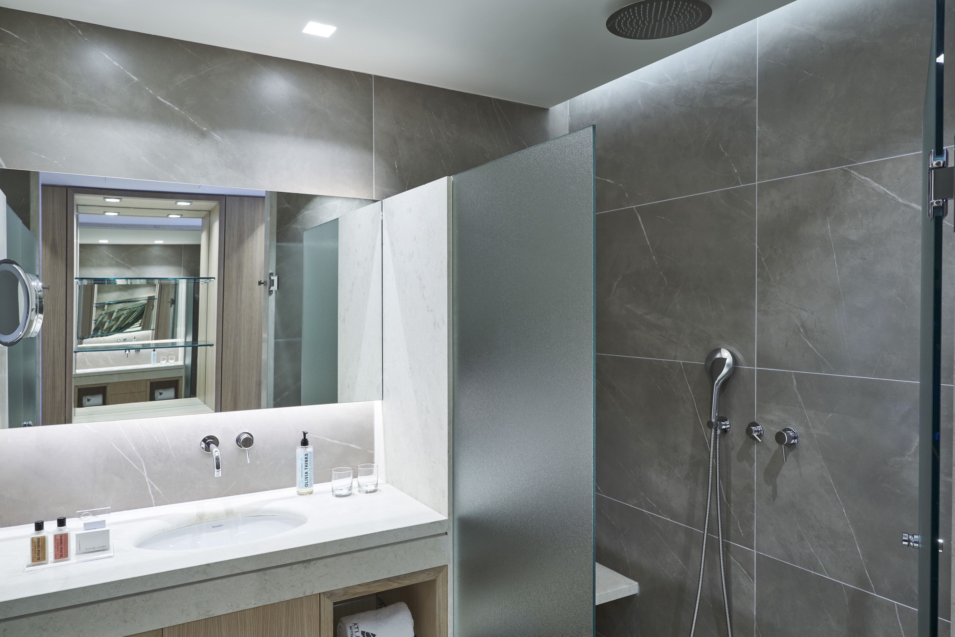 Un baño moderno con un espejo grande, un lavabo y una zona de ducha.