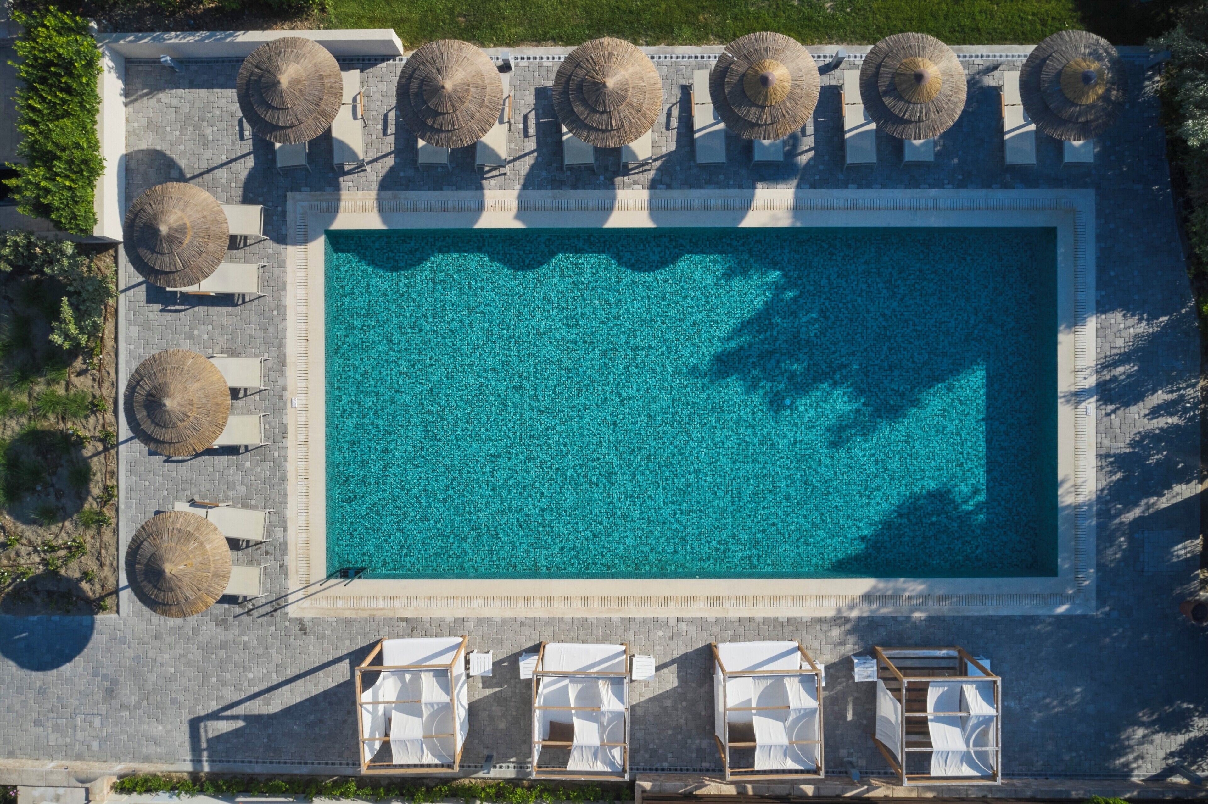 Vista aèria d'una piscina rectangular amb gandules i ombrelles.