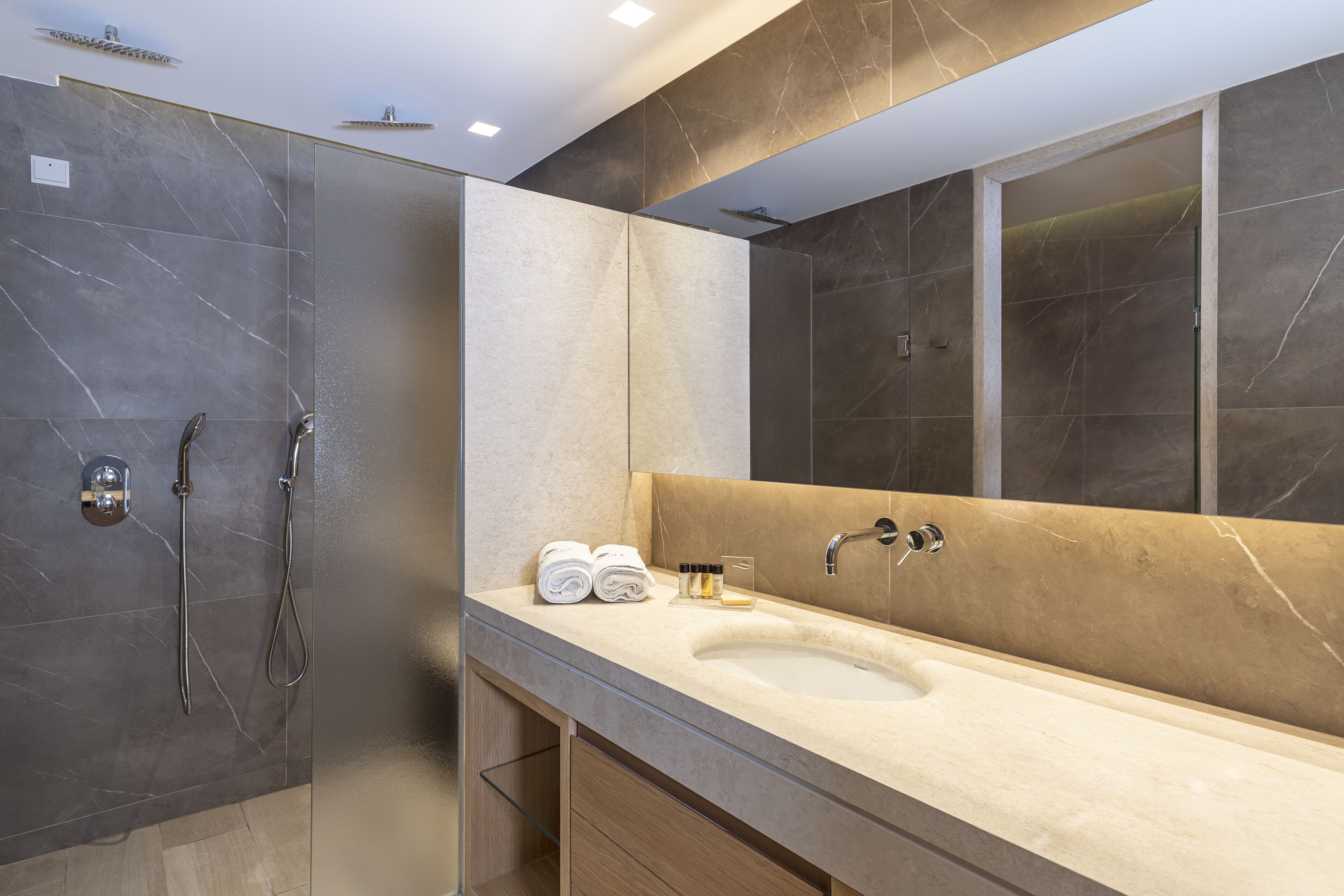 Un baño moderno con un espejo grande, un lavamanos y una ducha.