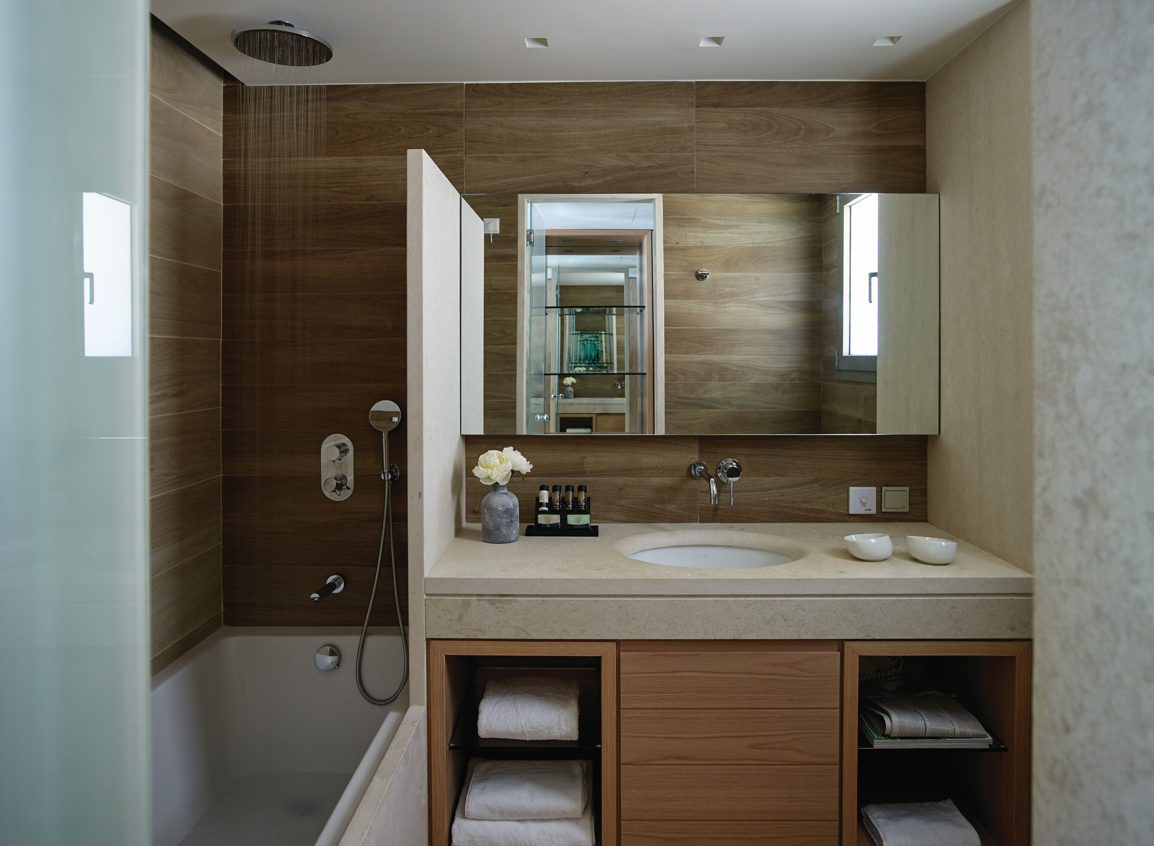 Un baño moderno con ducha a ras de suelo, tocador doble y un espejo grande.