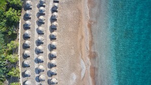 Vue aérienne d’une plage avec des rangées de parasols et de chaises longues.