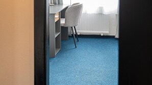 A room with a desk, chair, and a radiator.