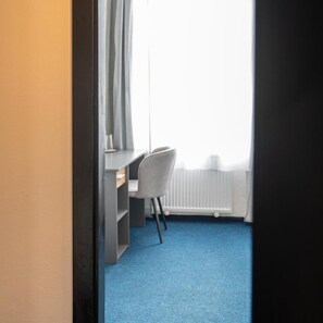 A room with a desk, chair, and a radiator. - CB Royal (CESKE BUDEJOVICE)