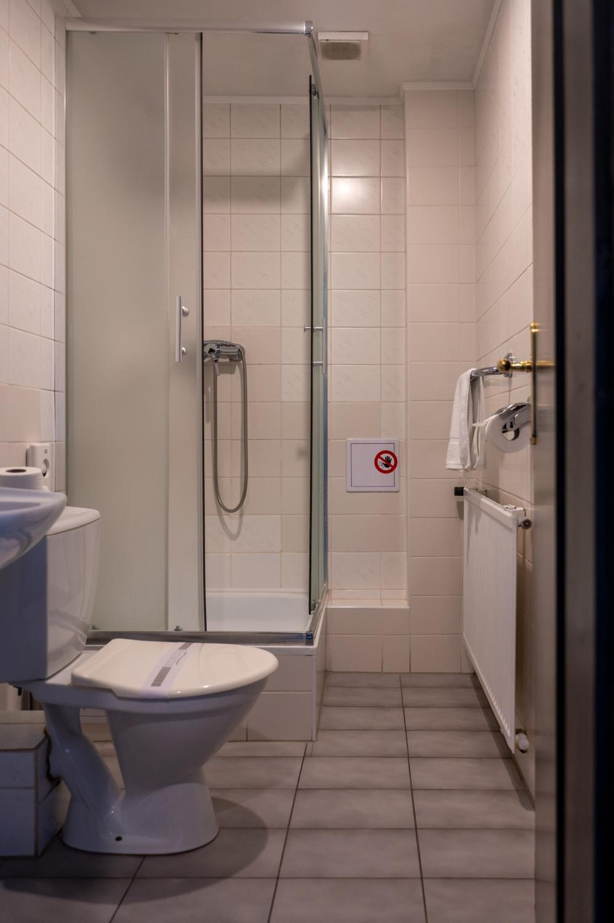 Une salle de bain avec douche, toilettes et porte-serviettes.