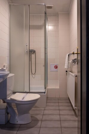 A bathroom with a shower, toilet, and a towel rack.