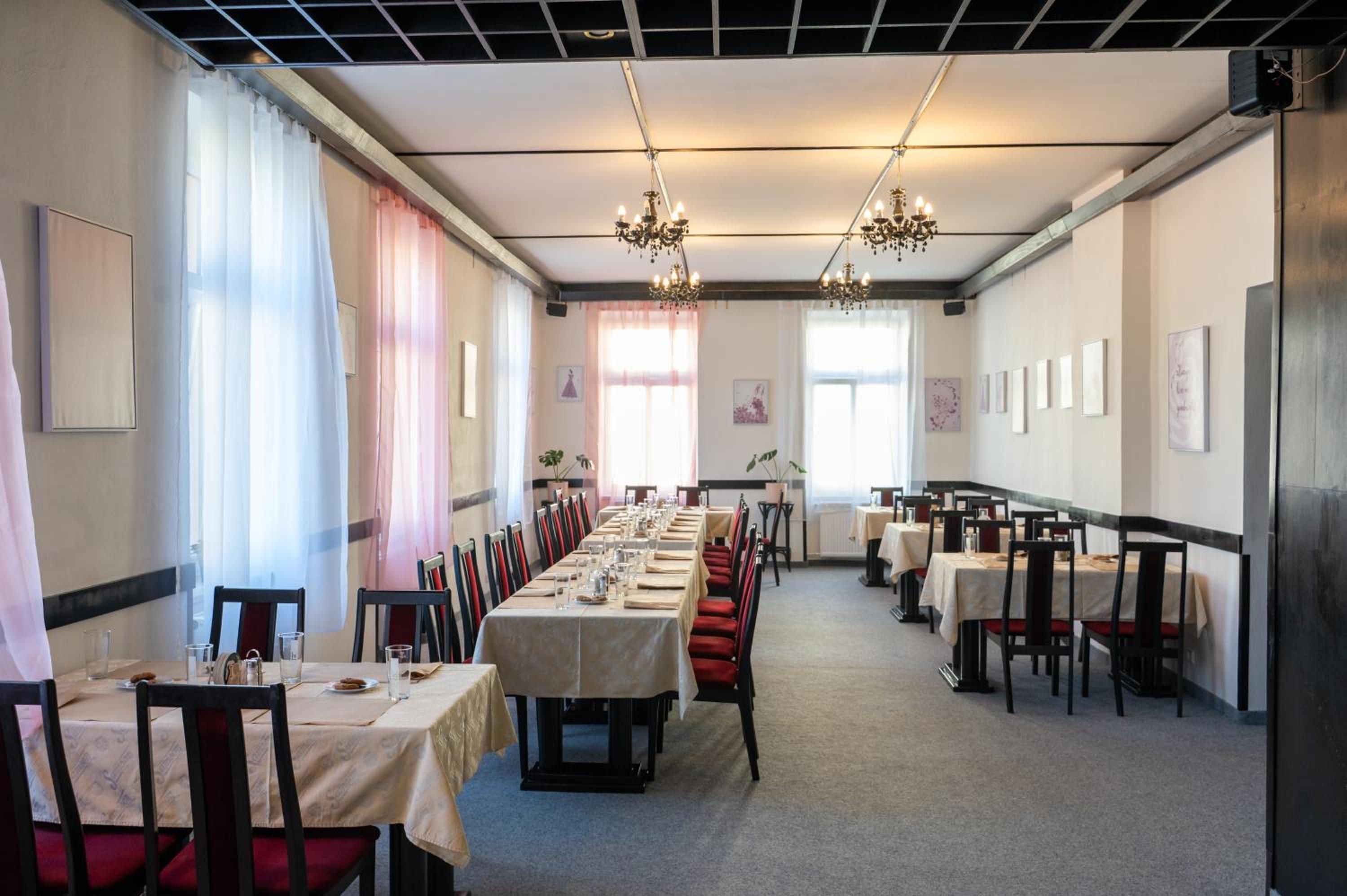 A conference room with long tables, chairs, and chandeliers.