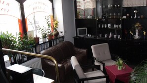 A room with a leather sofa, a wooden desk, a computer, a reception desk, and shelves with various items.