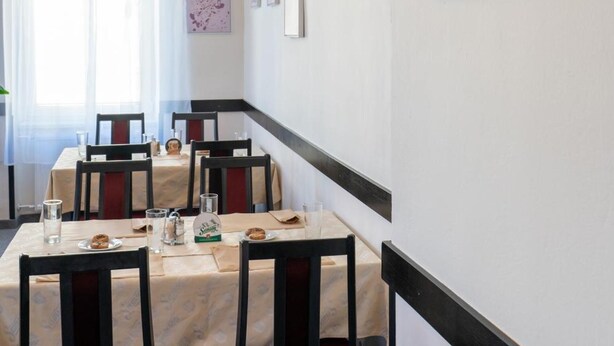 A dining area with a long table, chairs, and framed artwork on the walls.