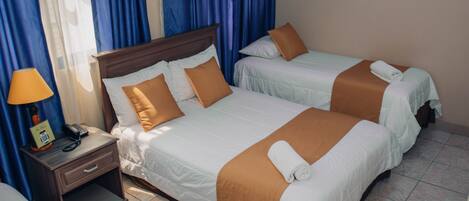 Habitación de hotel con dos camas, una mesita de noche con lámpara y teléfono.