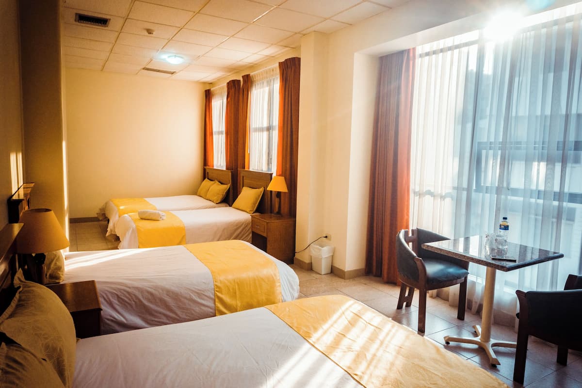 Habitación de hotel con dos camas, un escritorio y una silla.