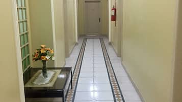 Un pasillo con suelo de baldosas, un extintor y una puerta al final.