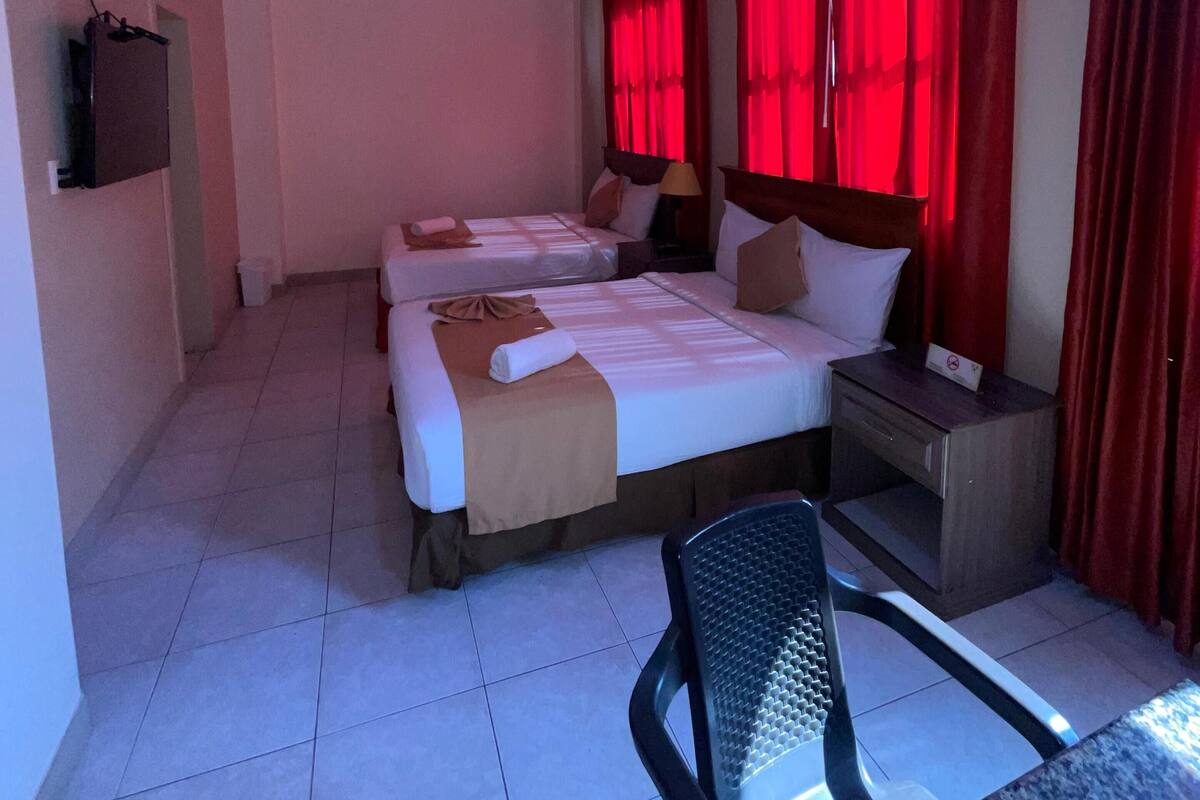 Habitación de hotel con dos camas, un escritorio y una silla. Se ve un llavero con el nombre del hotel y el número de habitación.