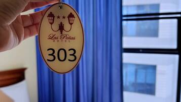 A hotel room with a bed, a window with blue curtains, and a keycard with the hotel name and room number.