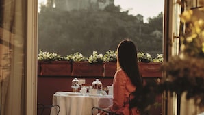 Una mujer sentada a una mesa con vista a un edificio y árboles.
