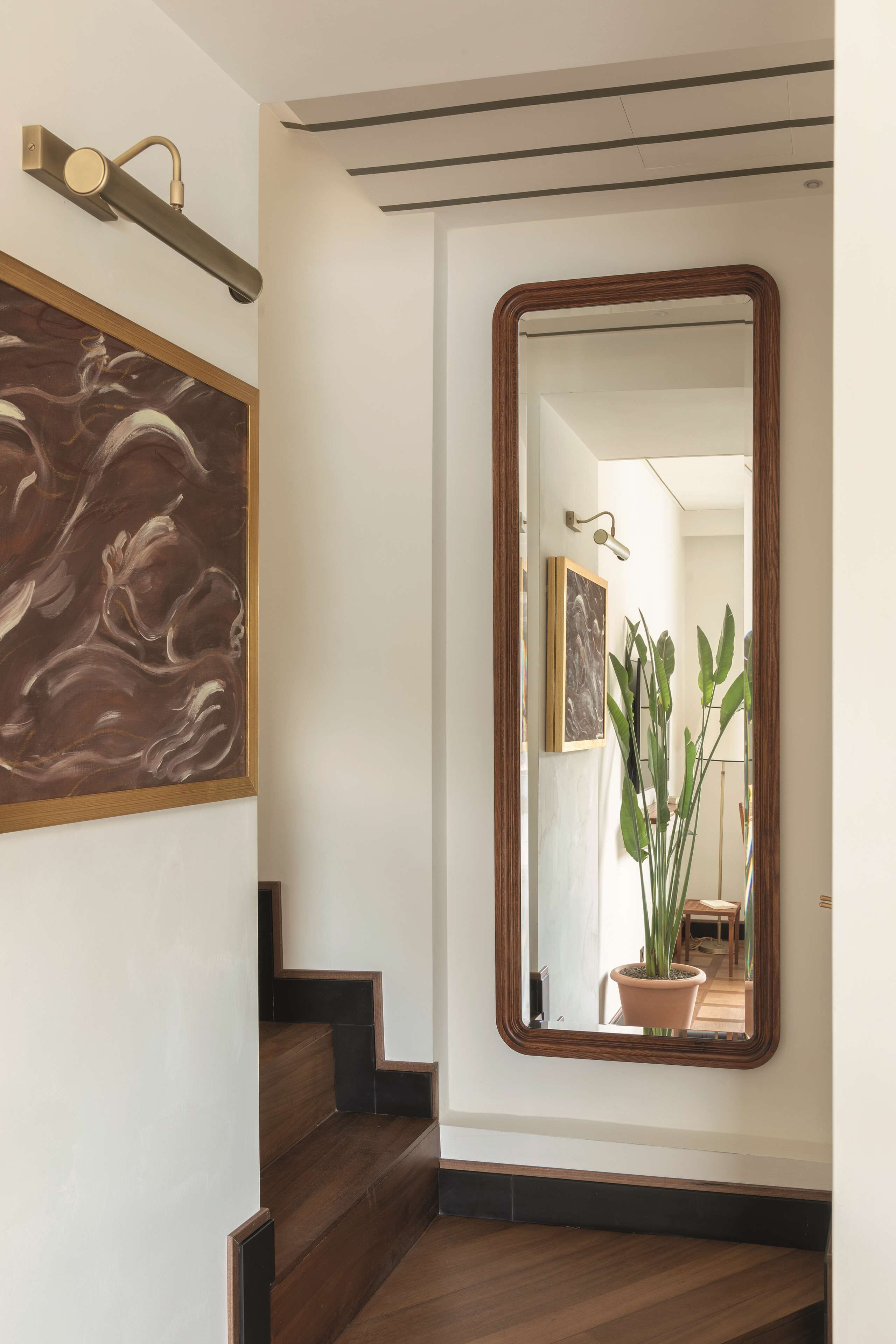 Eine Treppe mit Holzstufen, ein großer Spiegel und ein Gemälde an der Wand.