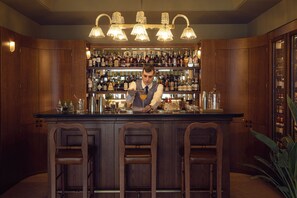 A bar area with wooden cabinets, a bartender, and a well-stocked liquor shelf.