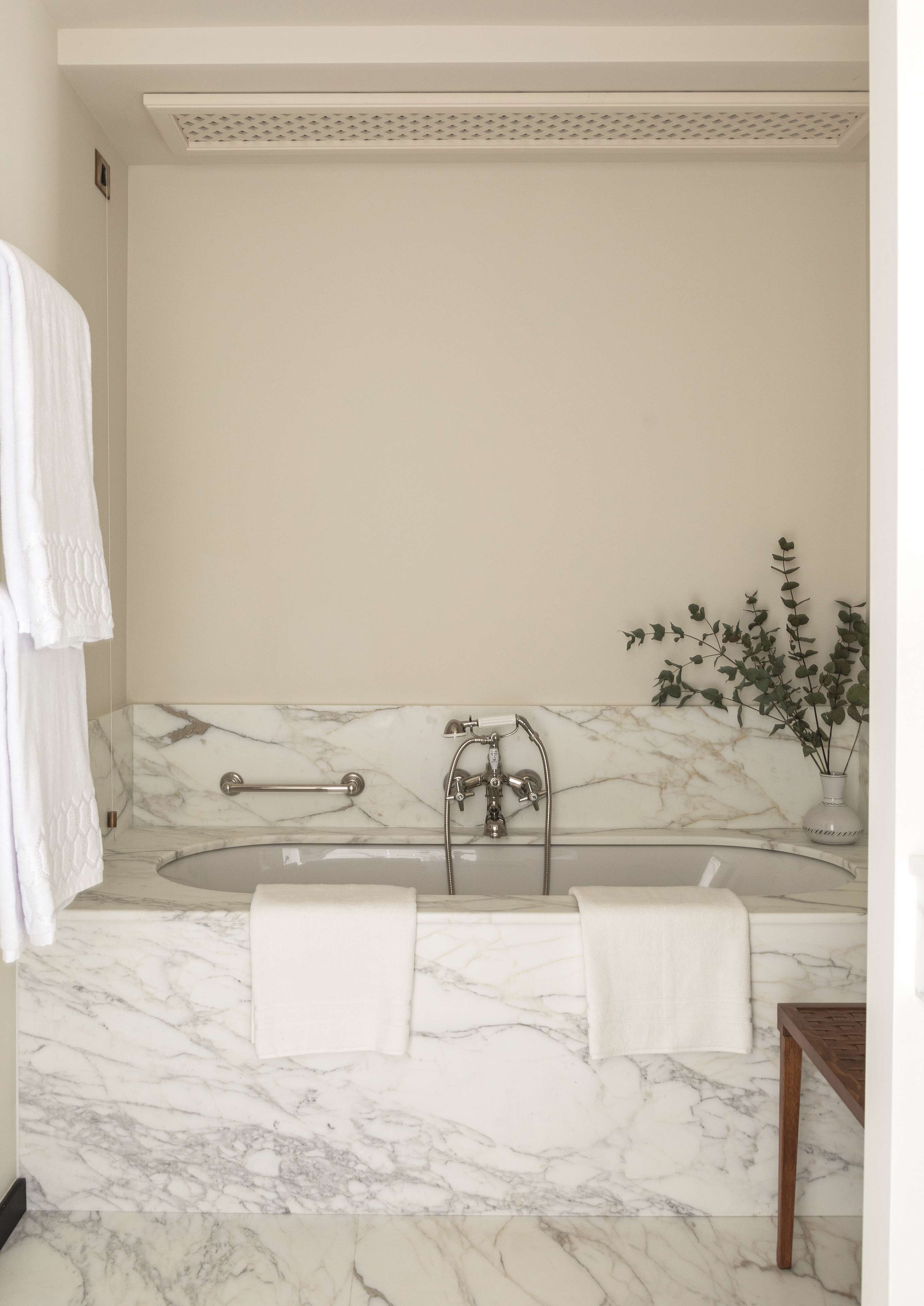 A bathroom with a marble floor, a bathtub, a shower, and a potted plant.