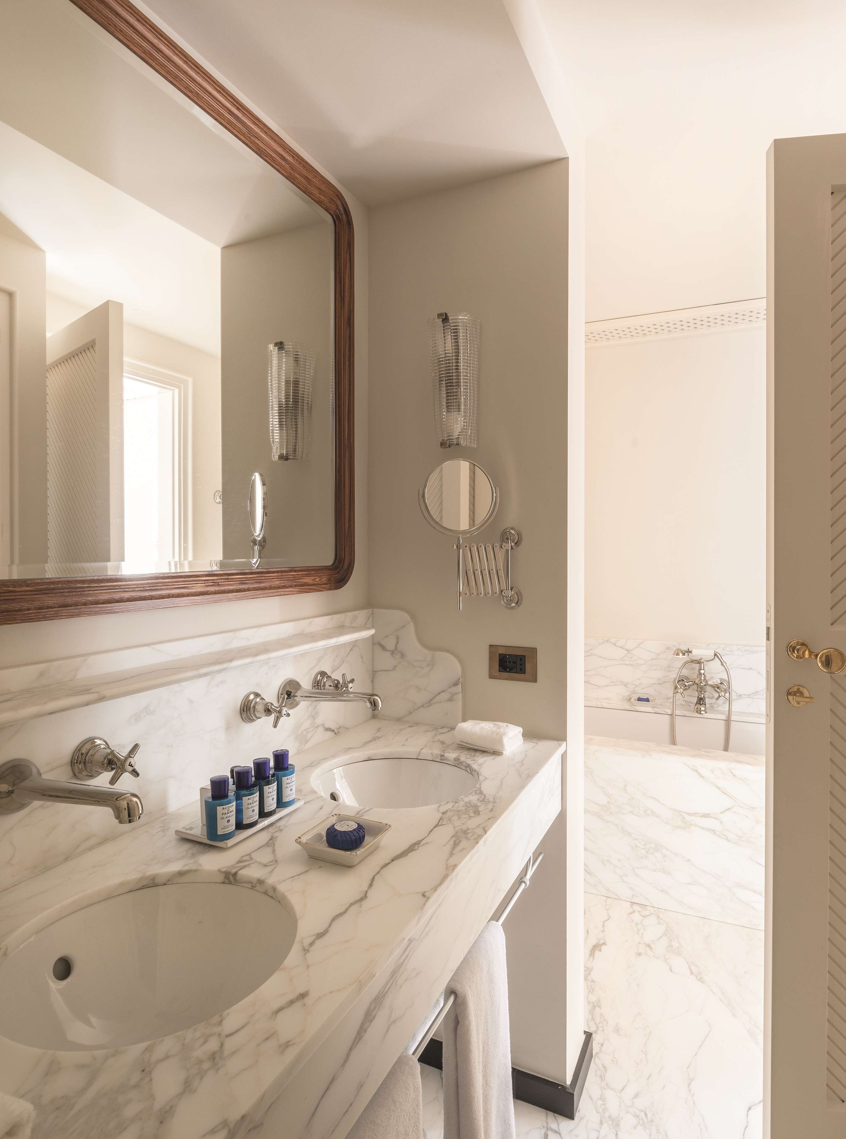 A bathroom with two sinks, a large mirror, a towel rack, and a shower area.