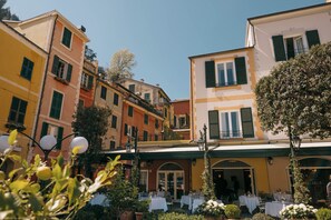 A courtyard with outdoor seating, surrounded by colorful buildings with balconies and green shutters. - Splendido Mare, A Belmond Hotel, Portofino (Portofino)
