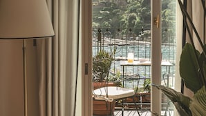Habitación con vistas a un balcón, una mesa, sillas y una lámpara.