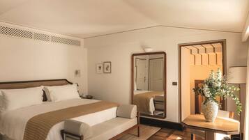 Ein Hotelzimmer mit Bett, Nachttisch, Spiegel und einem kleinen Esstisch mit Blumen.