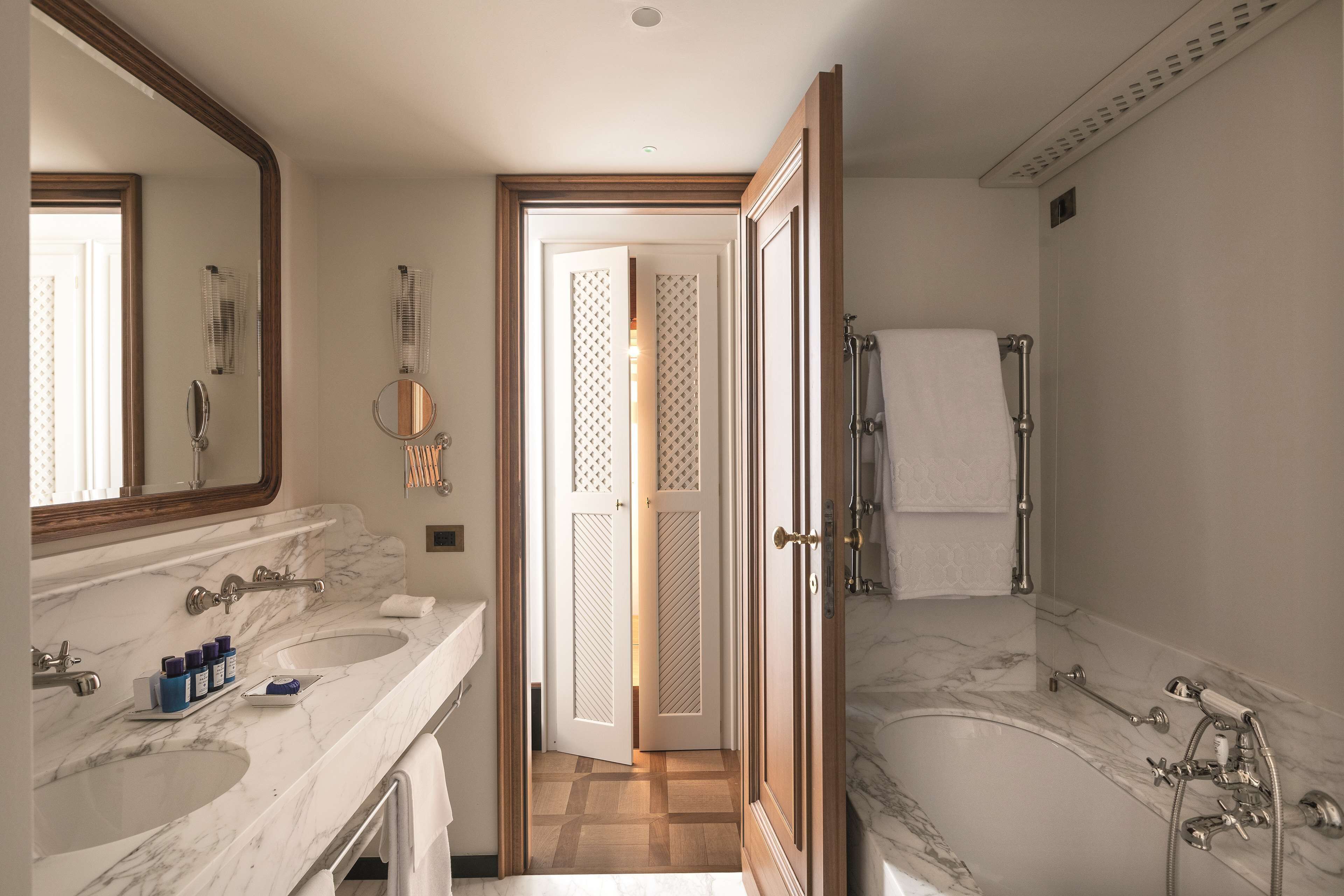 Een badkamer met twee wasbakken, een grote spiegel, een bad en een douche.
