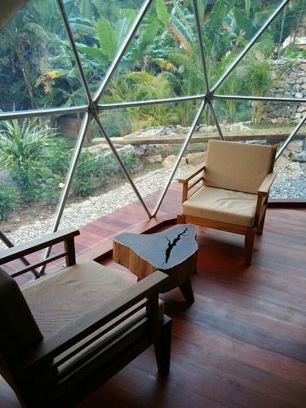 A room with a geometric glass partition, wooden furniture, and a view of a garden. - Keinnara Hpa An (Hpa-An)
