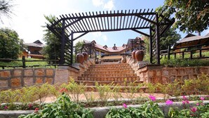 A stone staircase leading to a wooden pergola with large vases.