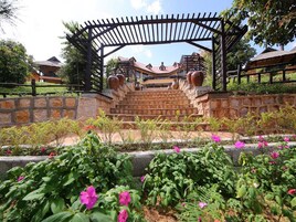A stone staircase leading to a wooden pergola with large vases.