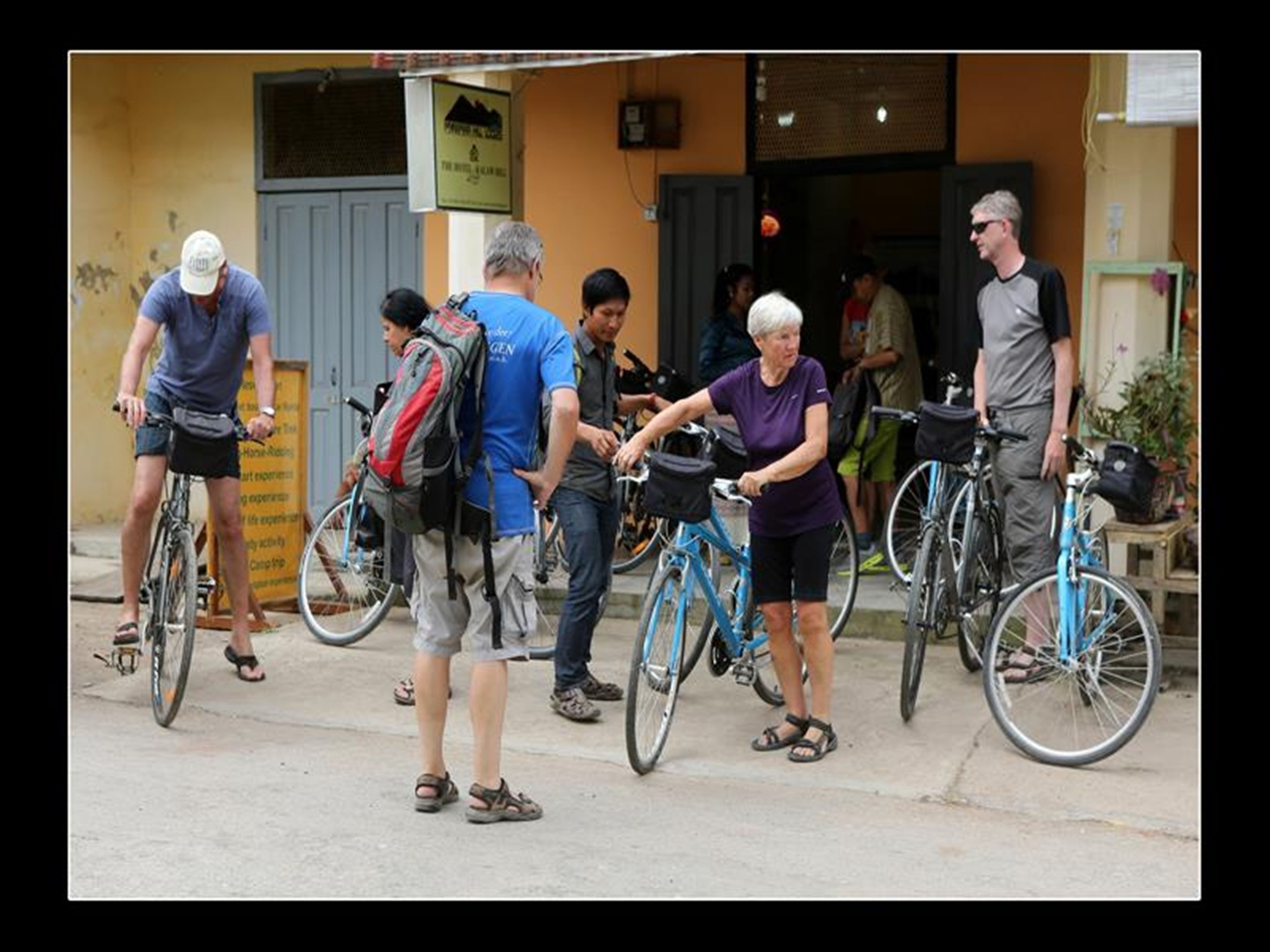 Un grupo de personas con bicicletas frente a un edificio, posiblemente un albergue o alojamiento.