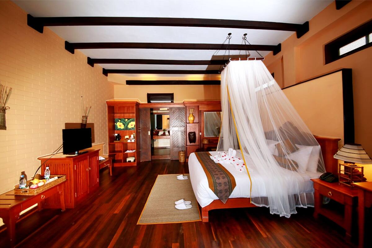 A bedroom with a bed, bedside table, TV, and a wardrobe.