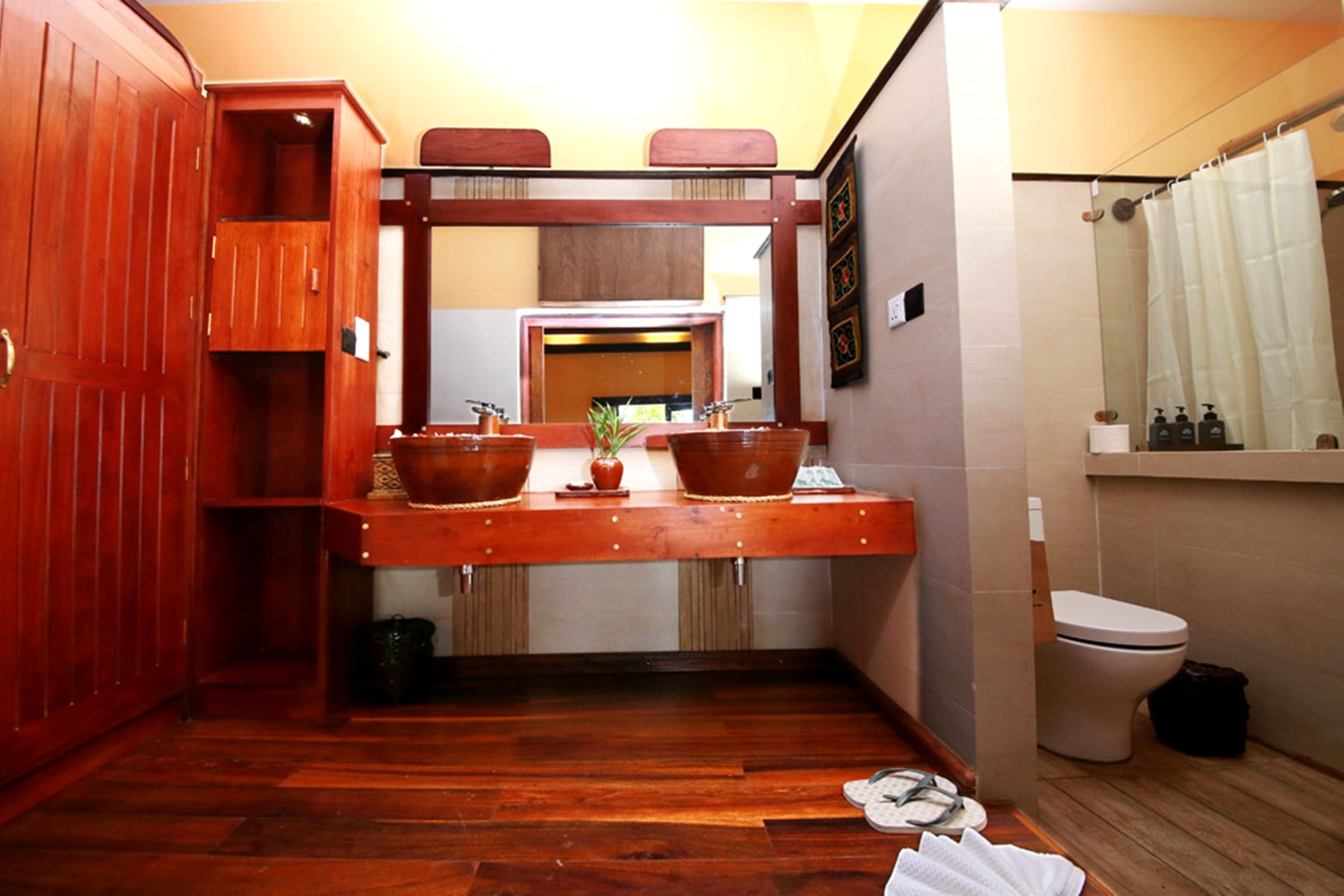 Een kleine badkamer met een houten wastafel, toilet en douchegordijn.