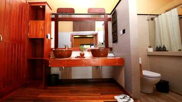 Een kleine badkamer met een houten wastafel, toilet en douchegordijn.