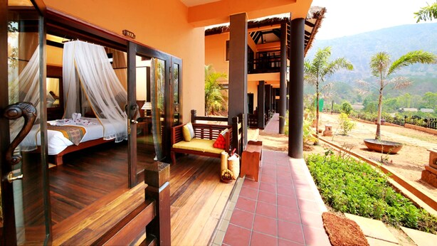 A room with a bed, a bench, and a view of the outdoors.
