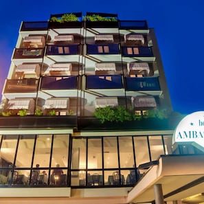 Ein mehrstöckiges Hotel mit Balkonen, ein Restaurant im Erdgeschoss und ein Schild mit der Aufschrift 'AMBAS'.