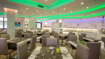 Ein Restaurant mit mehreren Tischen, Stühlen und einer Selbstbedienungszone.