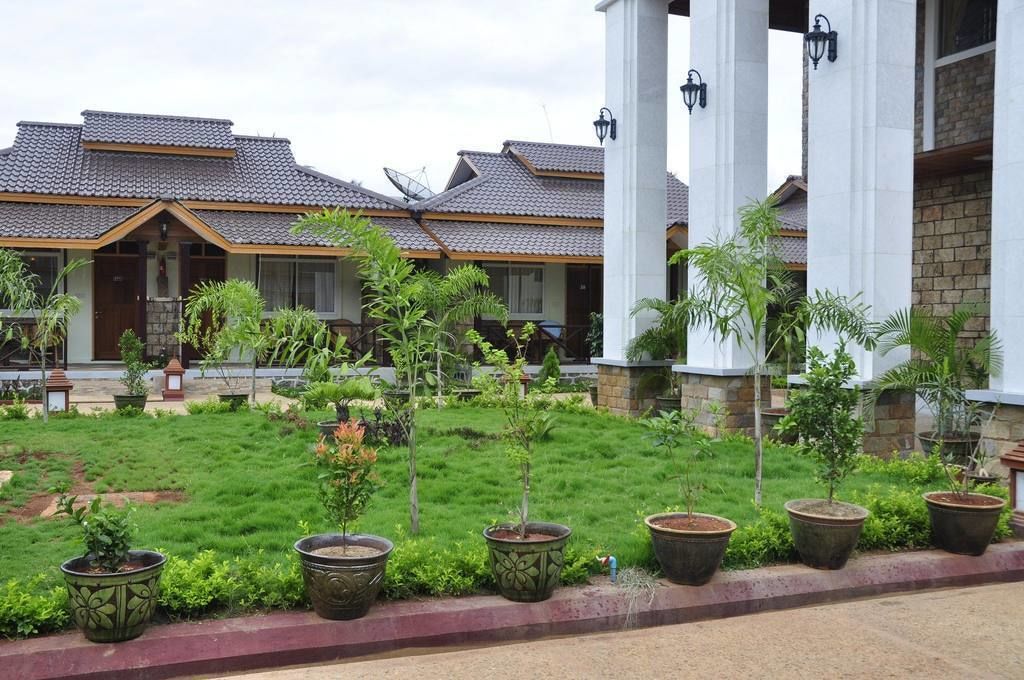 Un hotel con varias construcciones, cada una con tejado de baldosas y un jardín con plantas en macetas.