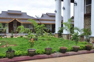Un hotel con varias construcciones, cada una con tejado de baldosas y un jardín con plantas en macetas.