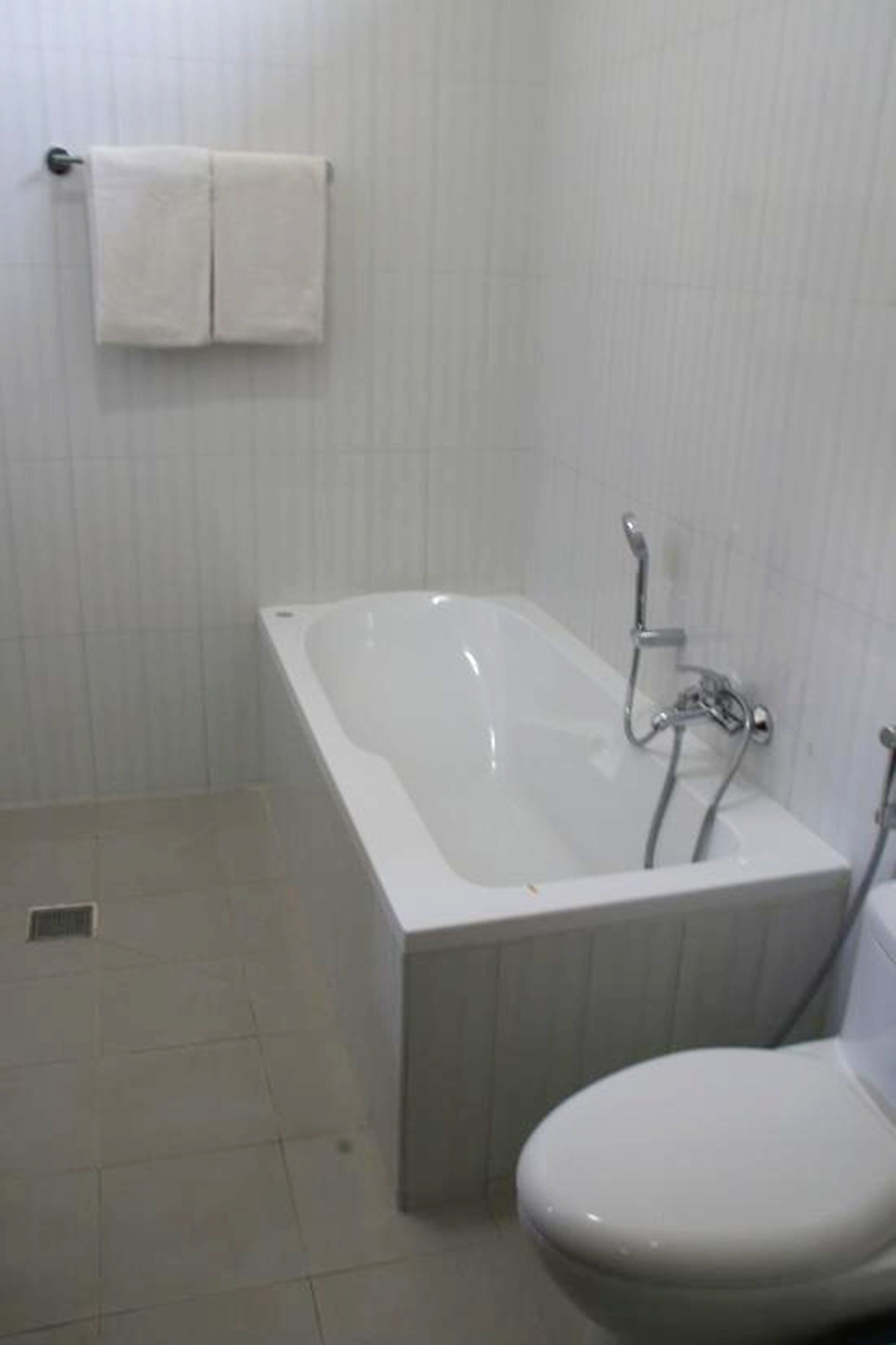 A bathroom with a bathtub, toilet, and a towel rack.