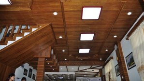 Un escalier en bois agrémenté d’un design moderne au niveau du plafond, comprenant des luminaires encastrés et une horloge.