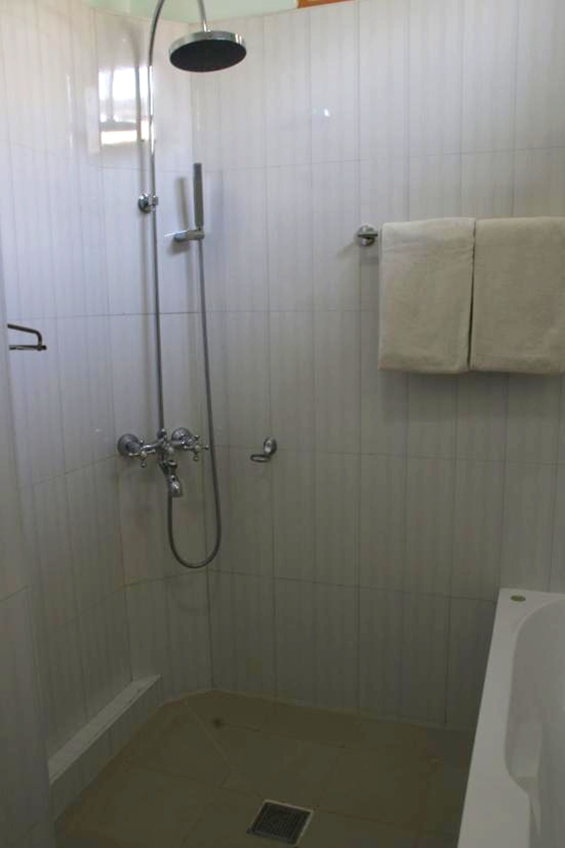 Um banheiro pequeno e revestido com azulejos, com chuveiro, vaso sanitário e banheira.
